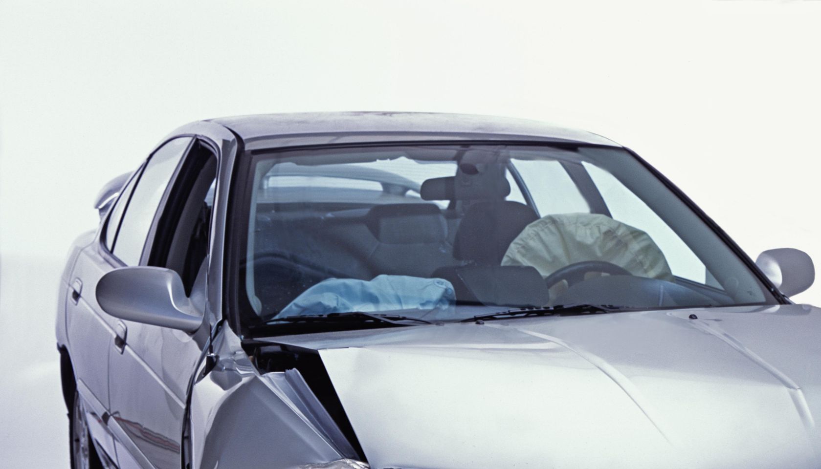 Silver sedan with front end damage and deployed airbags