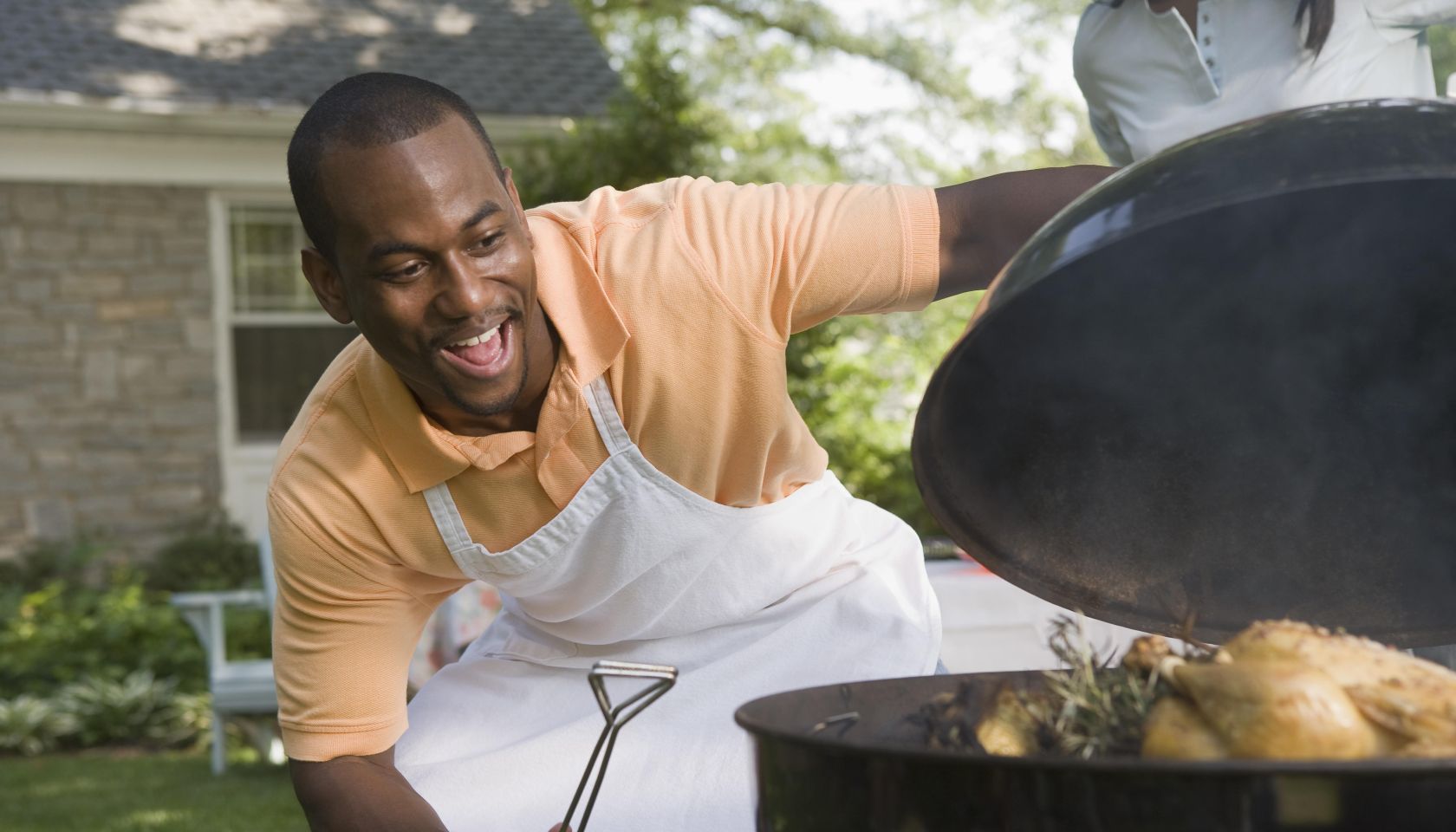 Smiling man cooking food on grill outdoors