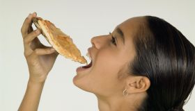 Young girl putting pizza into mouth
