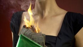 Woman holding pocketbook with money on fire