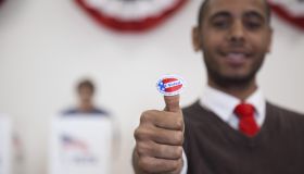 Hispanic voter holding an I Voted sticker in polling place