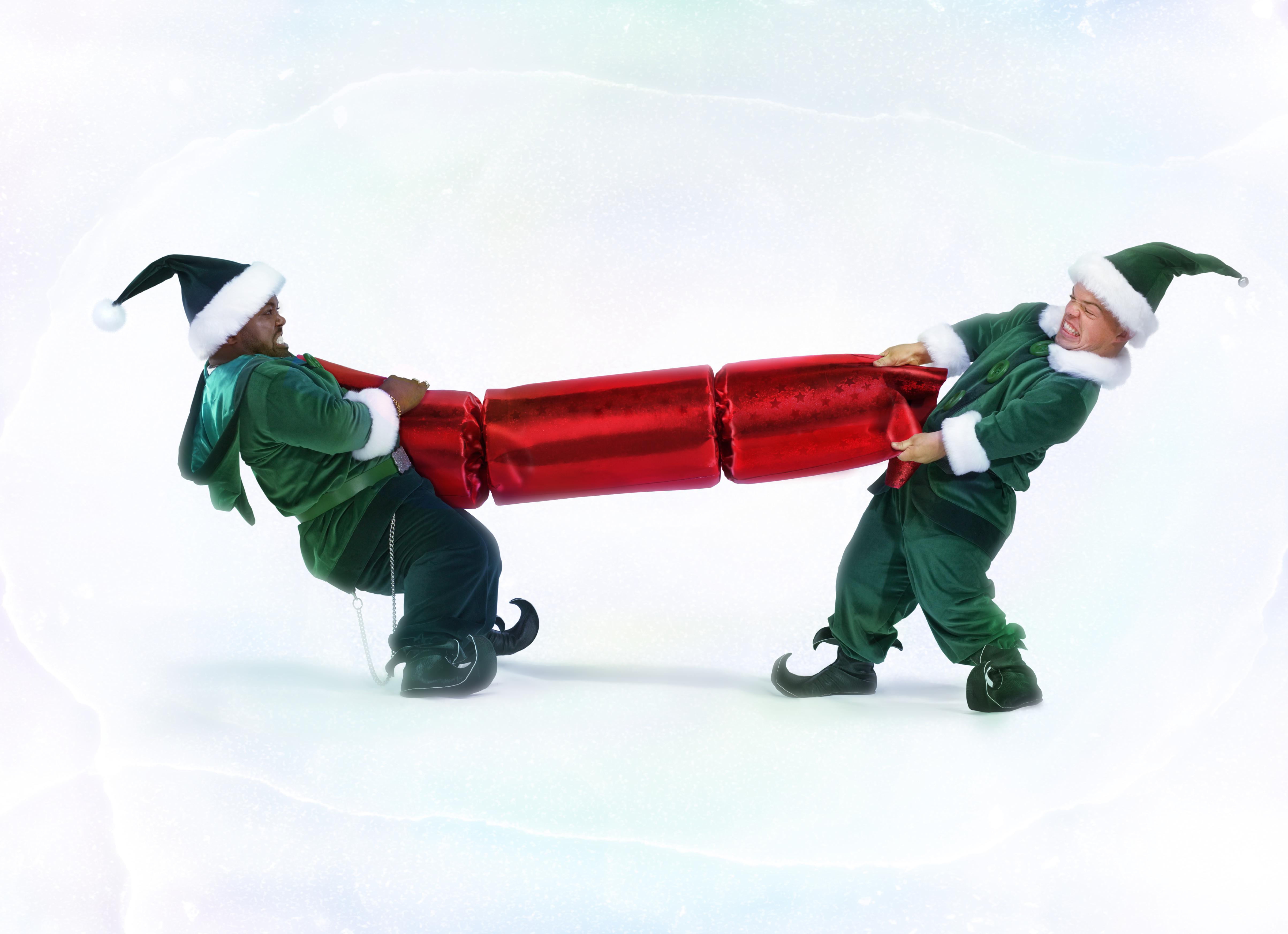 Two male 'elves' pulling large christmas cracker (digital enhancement)