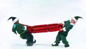 Two male 'elves' pulling large christmas cracker (digital enhancement)
