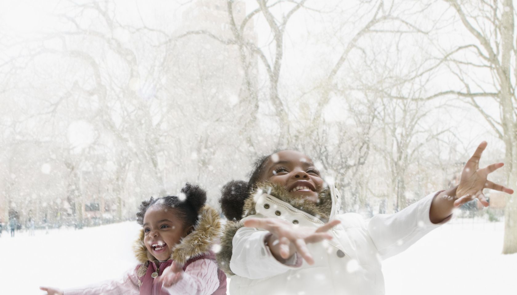 Mixed race girls catching snowflakes