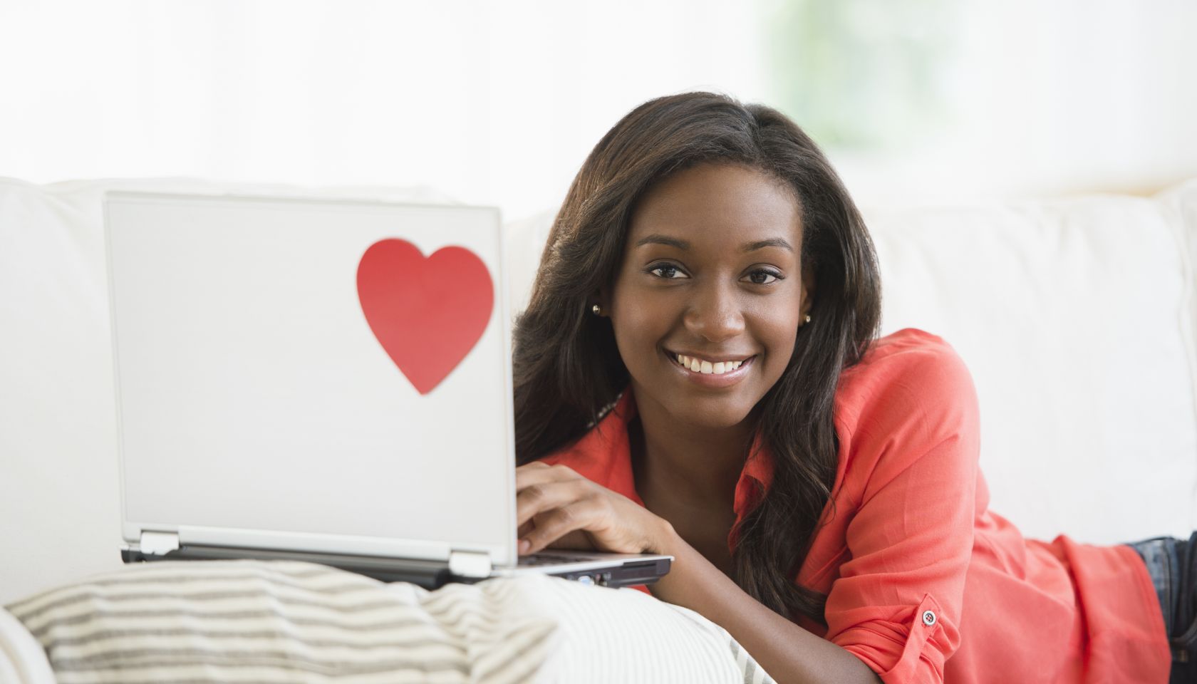 Black woman using laptop on sofa