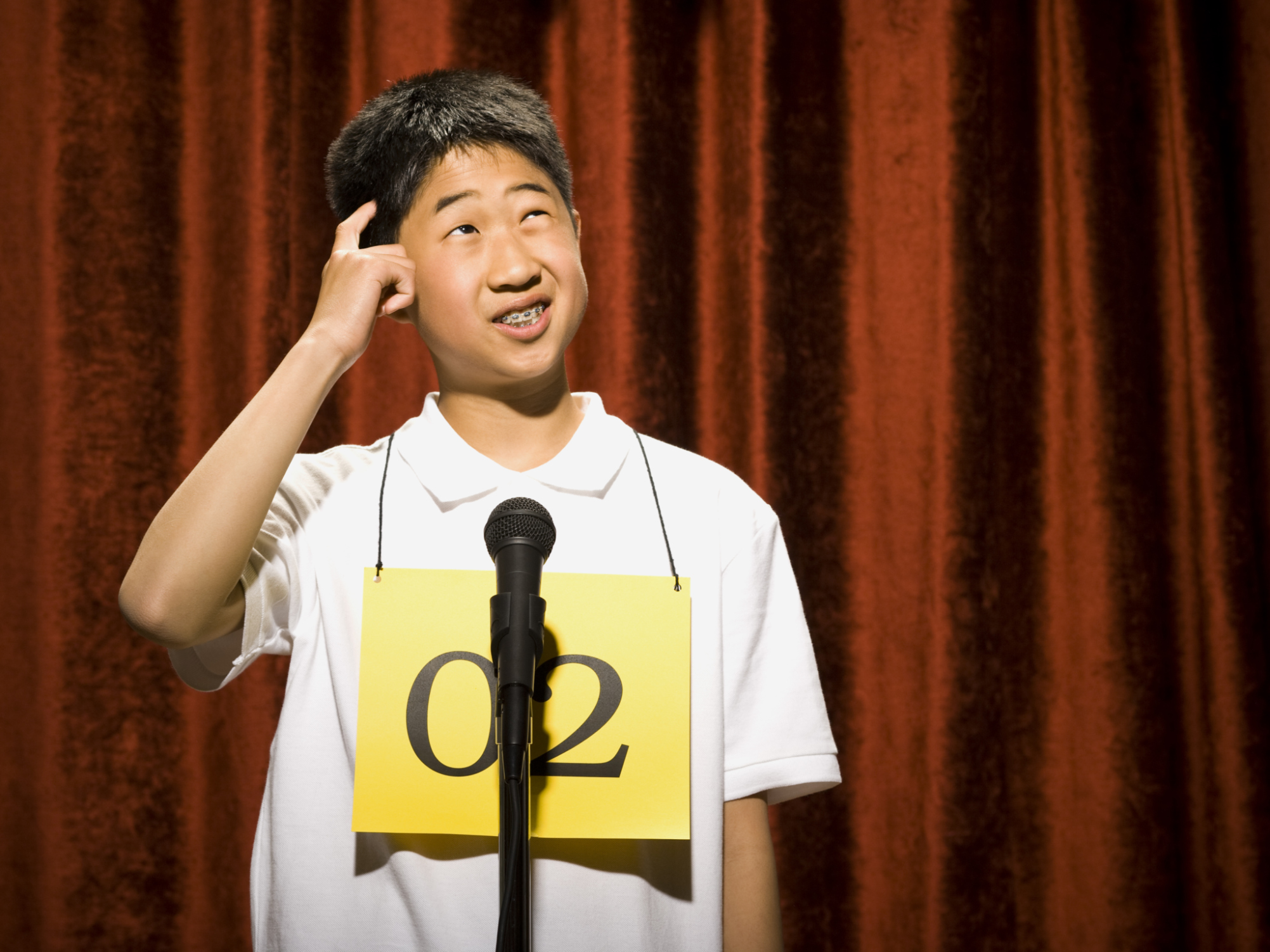Boy contestant standing at microphone thinking