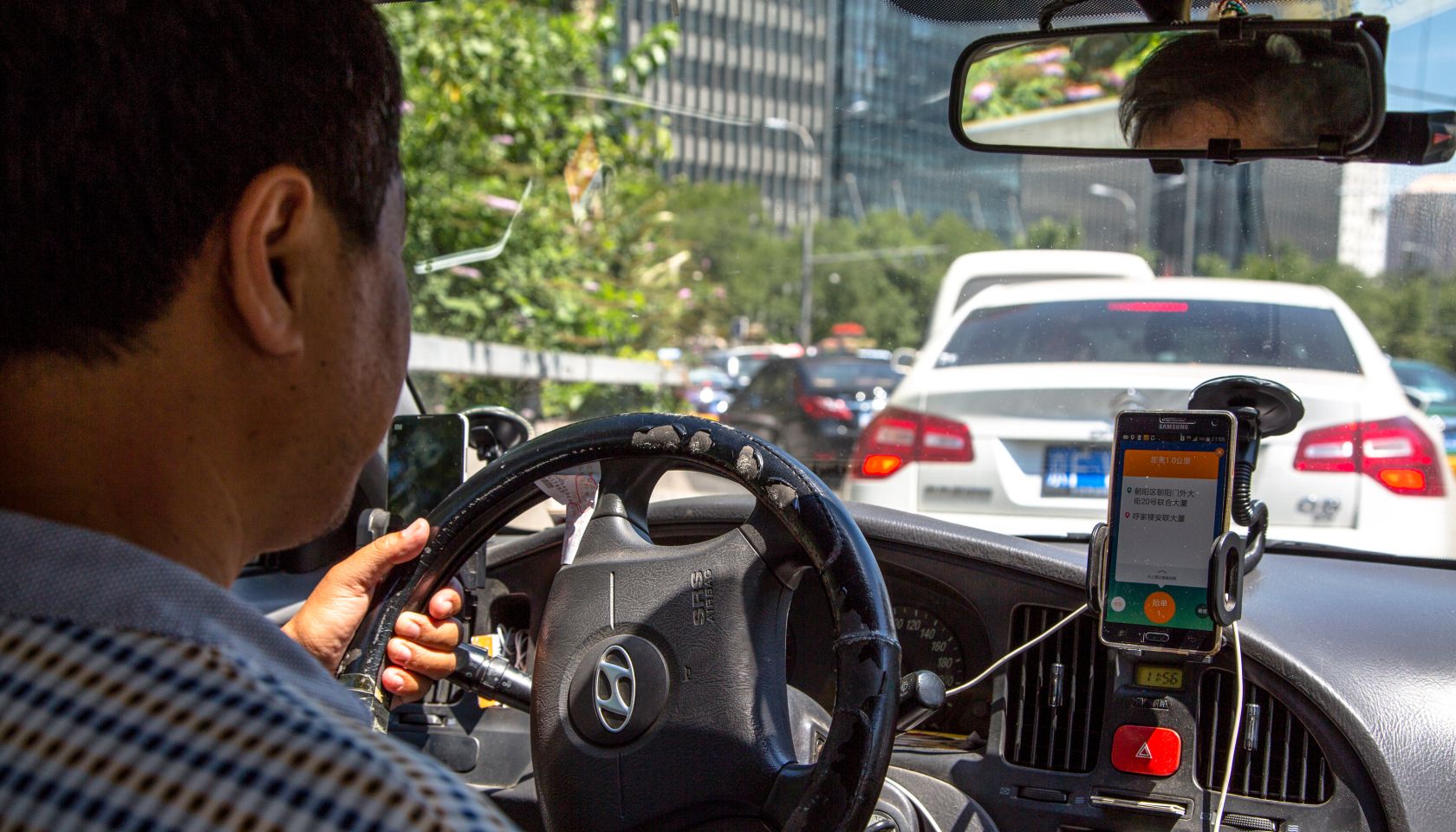 A taxi driver is using Didi Dacha App while driving on the...