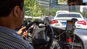A taxi driver is using Didi Dacha App while driving on the...