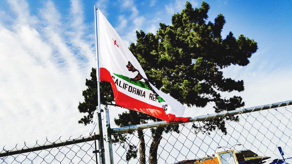 California Flag On Fence Against Cloudy Sky