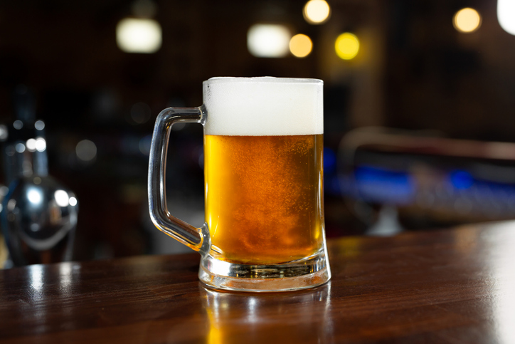 Glass of light beer on a dark pub.