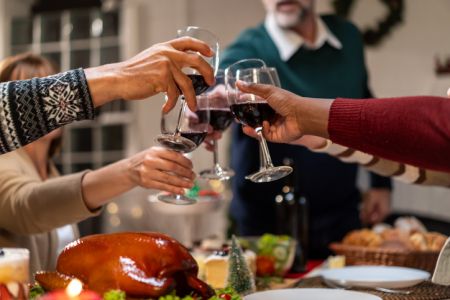 Multi-ethnic big family celebrating Christmas party together in house. Attractive diverse people having dinner and toasting a glass of wine to celebrate holiday Thanksgiving, X-mas eve on dining table