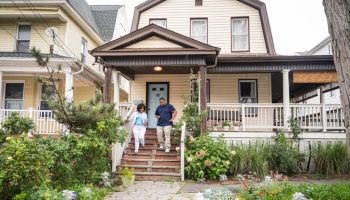 Black couple moving down front steps of two-story house