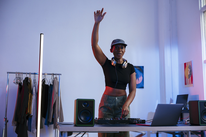 Happy DJ with arm raised operating sound mixer