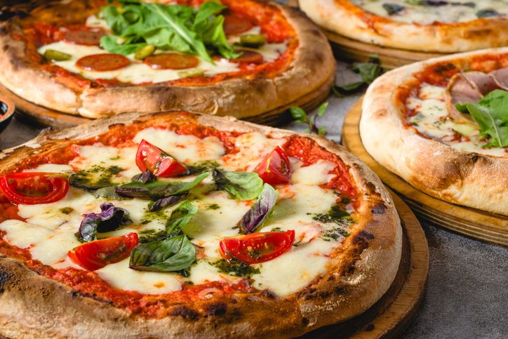 Top view of various neapolitan pizzas on grey stone table