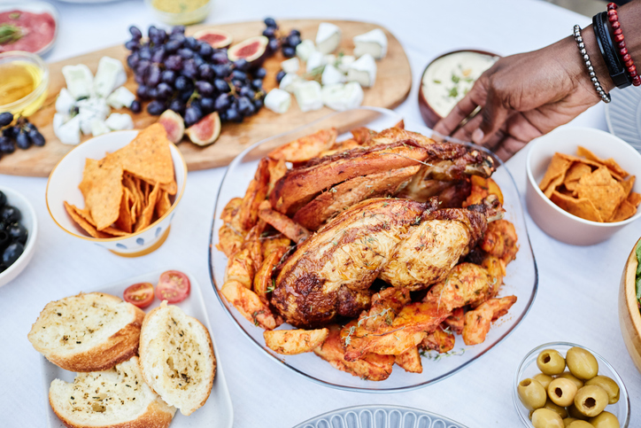 Close Up of Black Man Putting Roasted Chicken Dish on Table