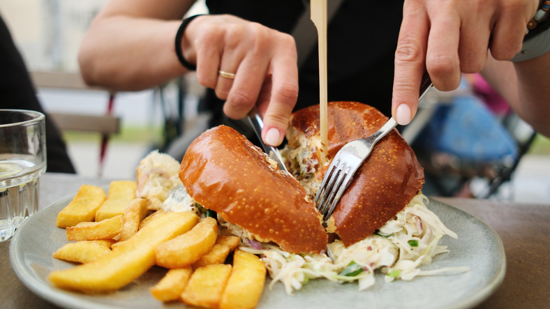 Girl Eating Fast Food Chips An Meat Burger In Cafe