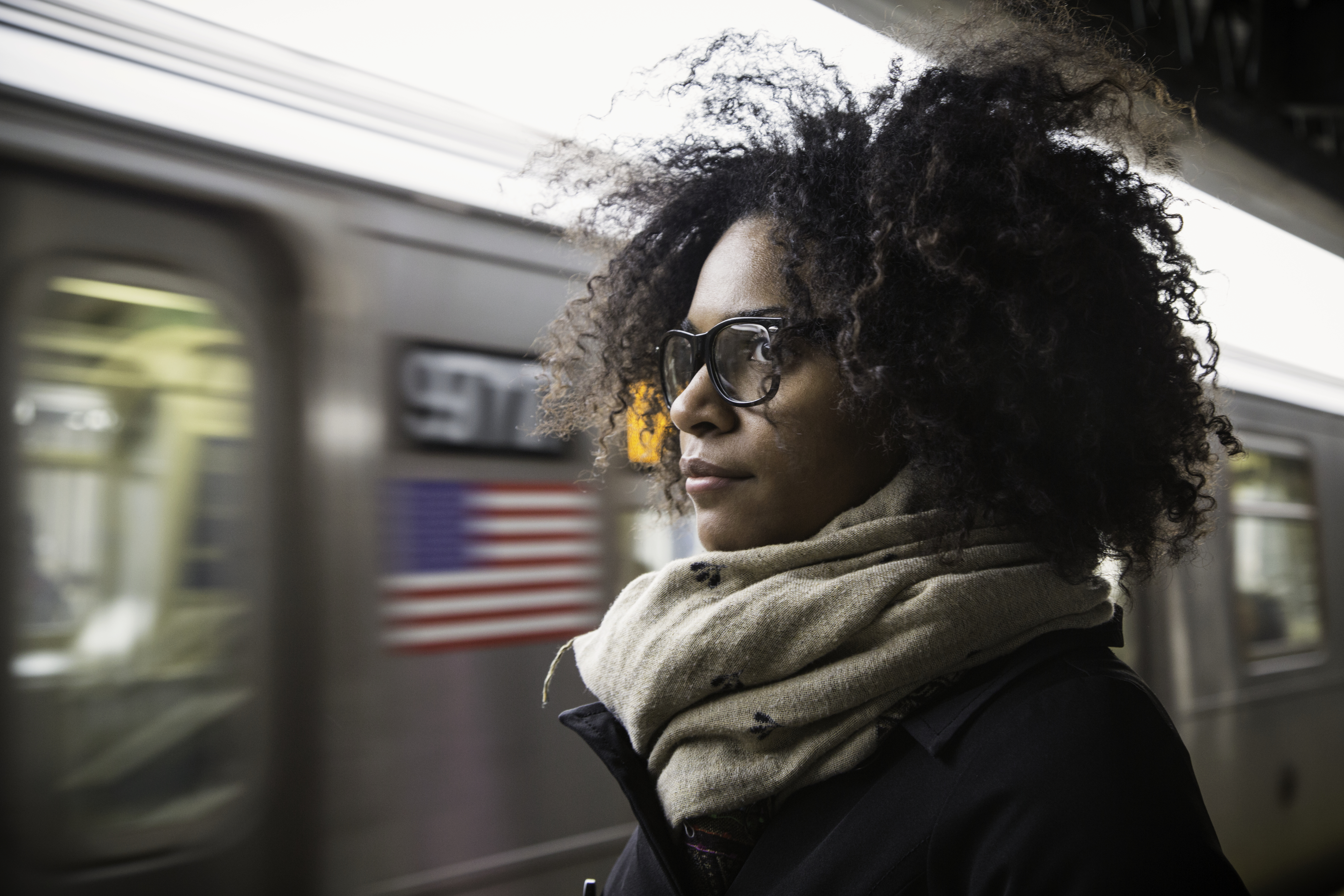 Woman waiting on an above-ground platform for the next subway train