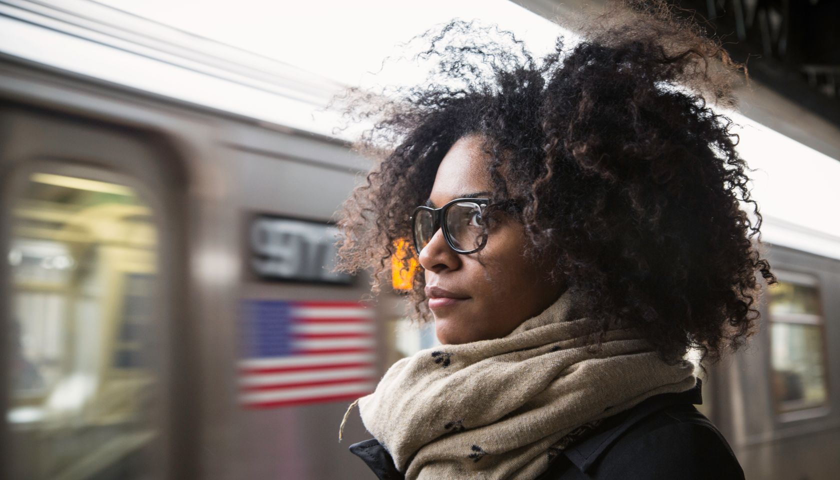 Woman waiting on an above-ground platform for the next subway train