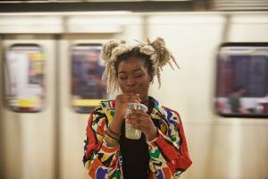 Black woman drinking from cup near subway