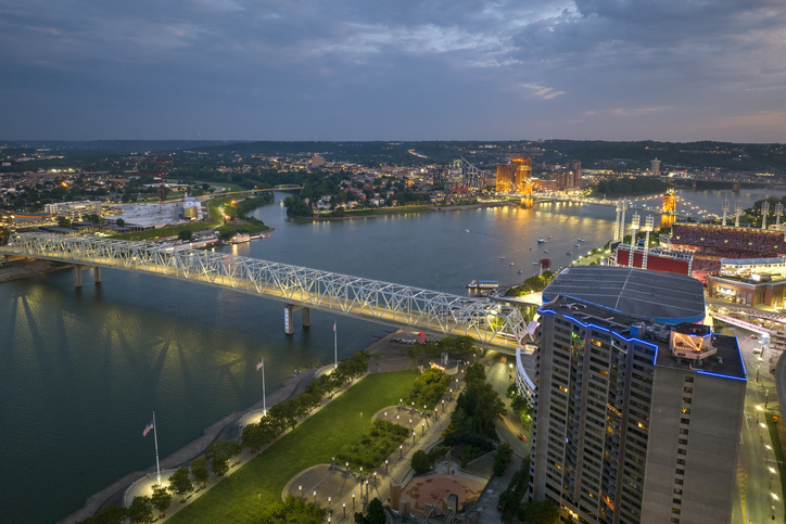Night urban landscape of downtown district of Cincinnati city in Ohio, USA. Skyline with bridge traffic and brightly illuminated high skyscraper buildings in modern American megapolis
