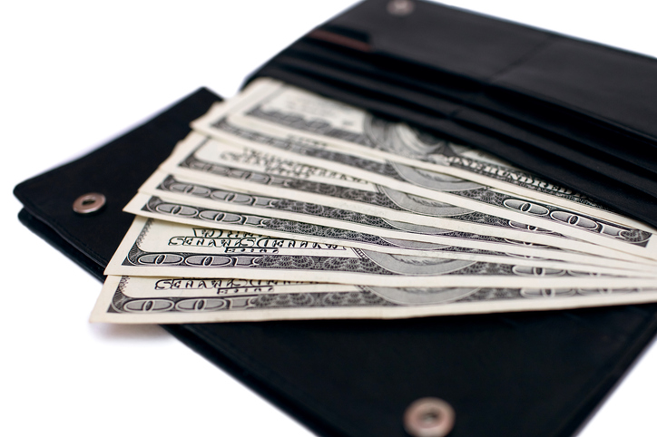 Cash from one hundred dollar bills in a wallet on a white background