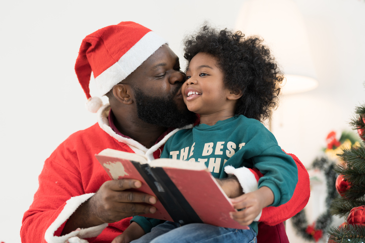 African American family reading book together at home. African American father and son reading book on Christmas day