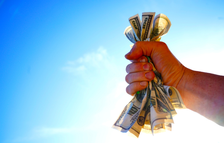 Dollars in hand on blue sky. Crumpled pile of dollar bills in male hand on sky, space for text.