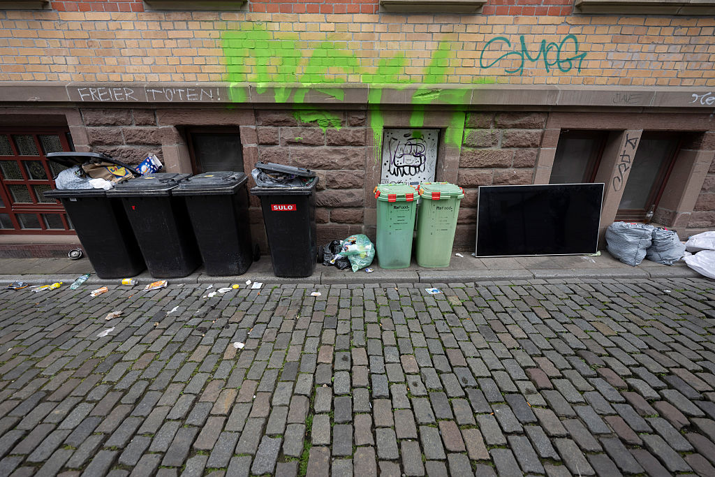 Overflowing garbage cans and litter in alleyway