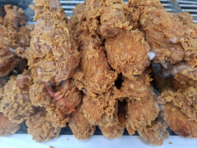 close up shot of crispy golden brown fried chicken displayed behind a glass showcase