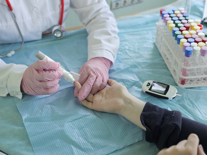 Medical professional performs blood test on patient in clinical setting using a device