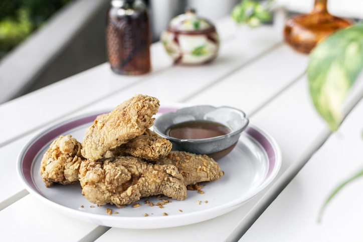 crispy breaded deep fried chicken pieces snack on white table in outdoor cafe