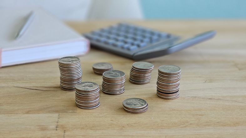 Stacks of coins on wooden table next to calculator