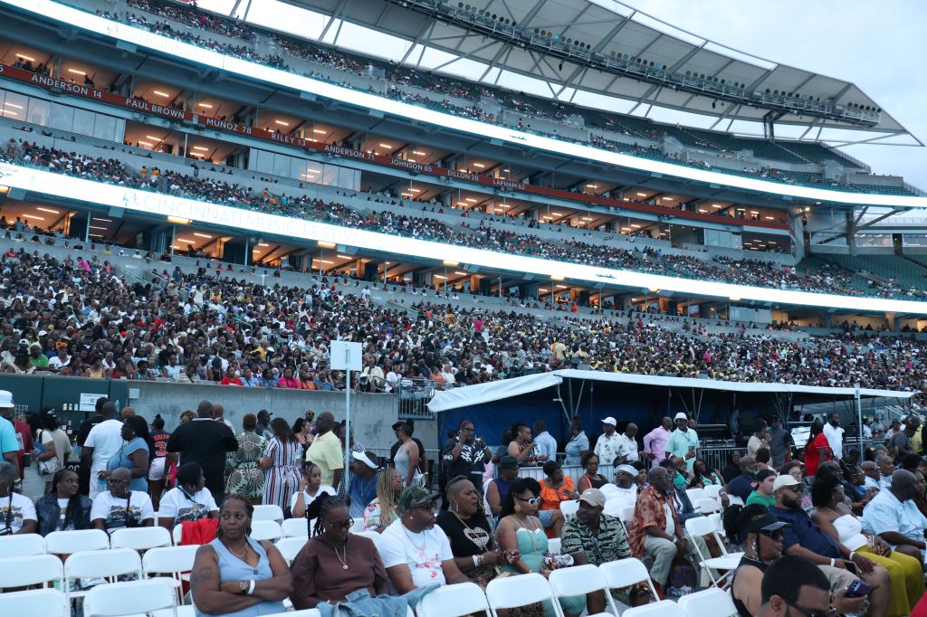 Crowded stadium with spectators in the stands and people in the foreground. The stadium has signage for "Anderson", "Paul Brown", "Munoz", and "Lelie".