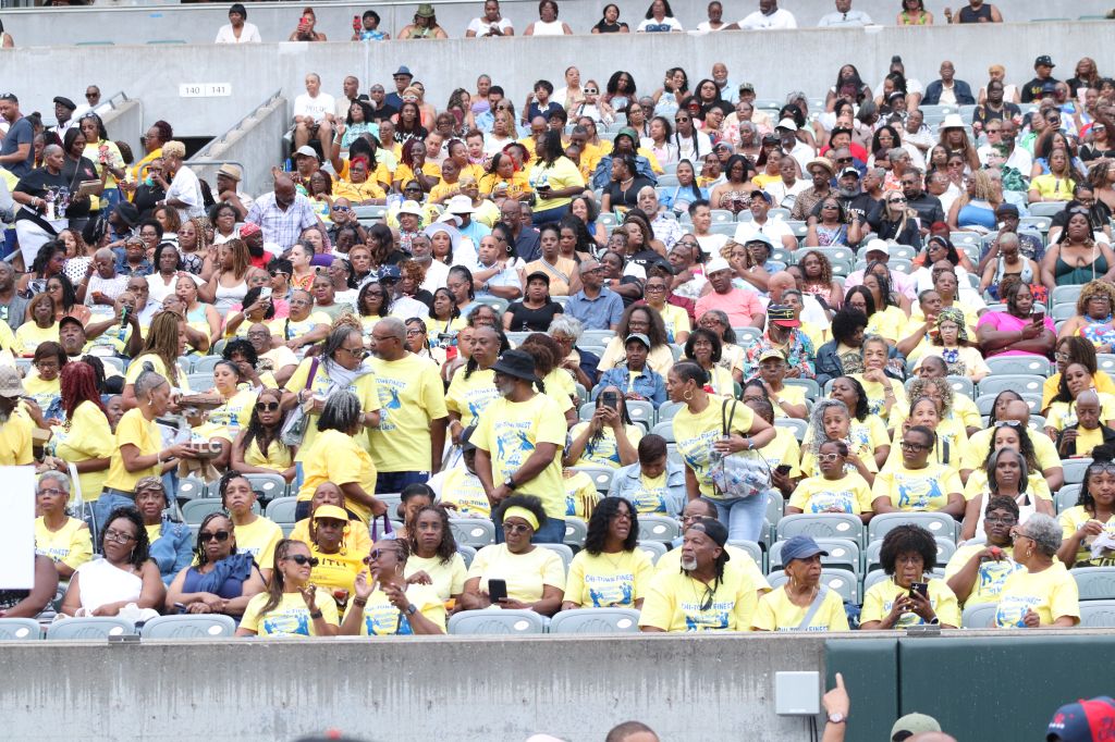Large crowd of people wearing yellow shirts gathered in a stadium