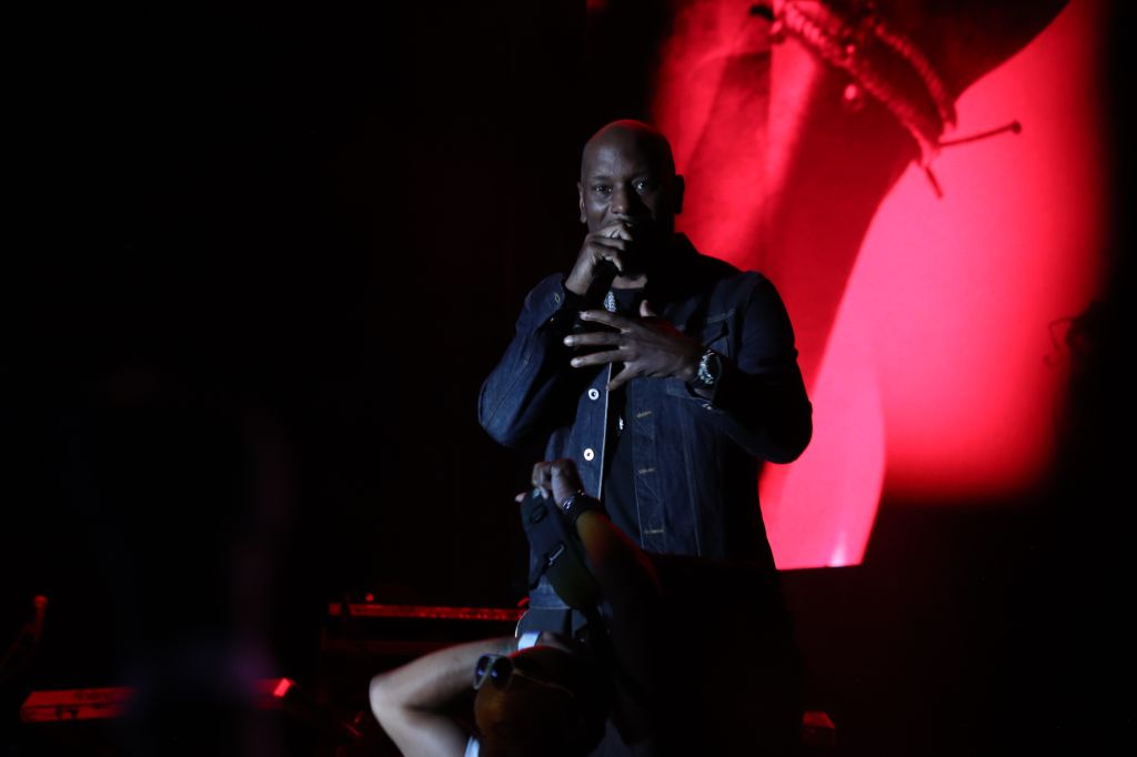 A person in a dark jacket standing on a stage, silhouetted against a red light.