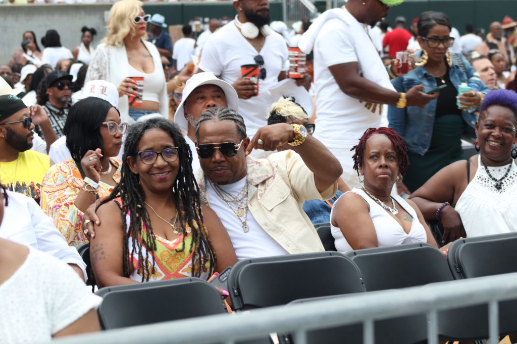 Diverse crowd of people gathered at an outdoor event, some wearing colorful clothing and accessories.