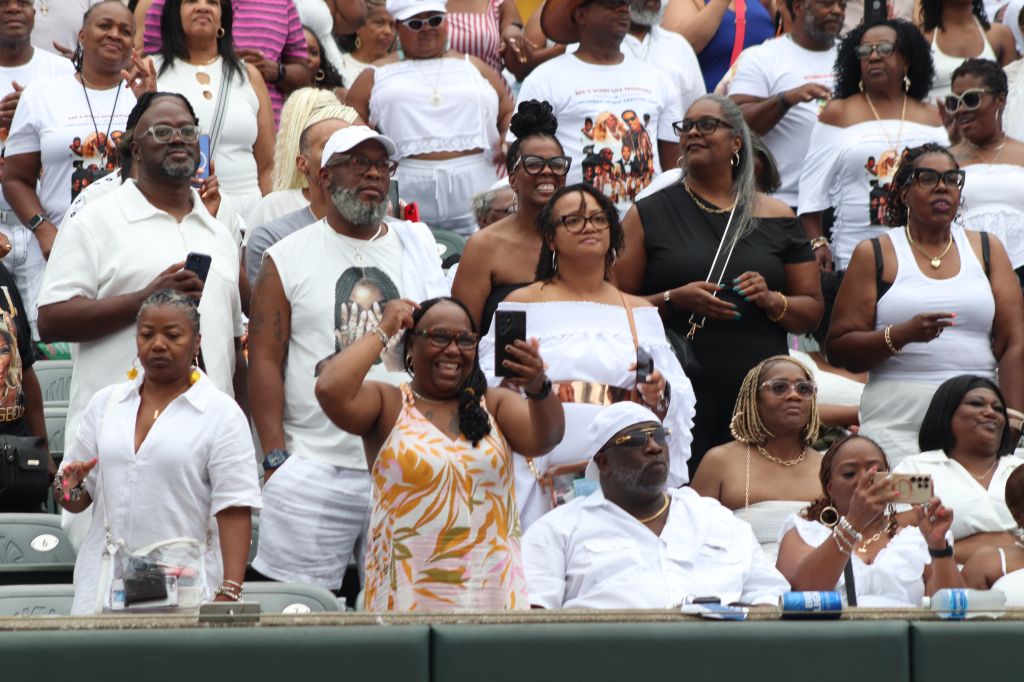 A large crowd of people wearing white clothing and holding signs at an event or rally.